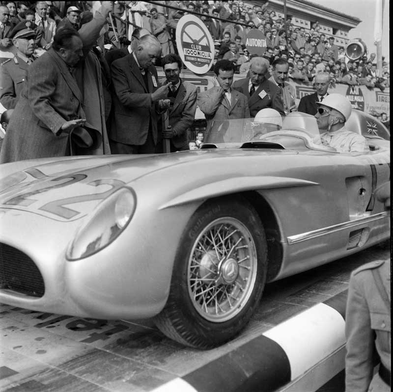 Amura,AmuraWorld,AmuraYachts, Stirling Moss y Denis Jenkinson después de recibir la bandera a cuadros como vencedores de la Mille Miglia de 1955 a bordo del Mercedes-Benz 300 SLR.