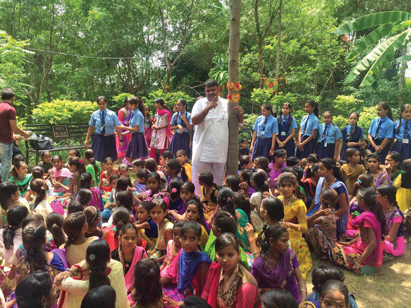 Shyam Sunder Paliwal, fundador del movimiento, rodeado por las niñas y naturaleza de Piplantri.